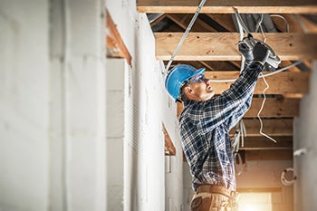 An electrician installs equipment at a construction site.