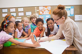 A Western student works on a project with a group of kids in a classroom.