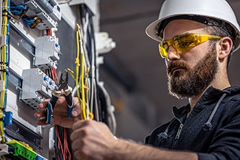 An electrician works with cords and electronics at a worksite.