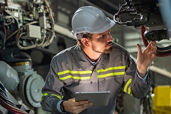 A technician inspects a large machine at a worksite.