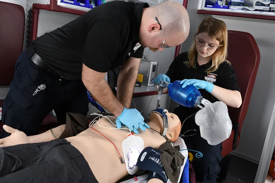 EMT students practice resuscitation techniques on a dummy.