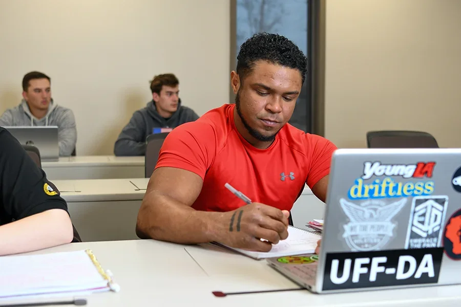 A business student takes note on his laptop during a lecture.