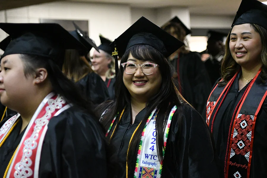 Hmong students with colorful sashes and their caps and gowns at graduation