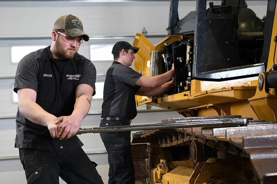 Students work with large machines in a workshop.