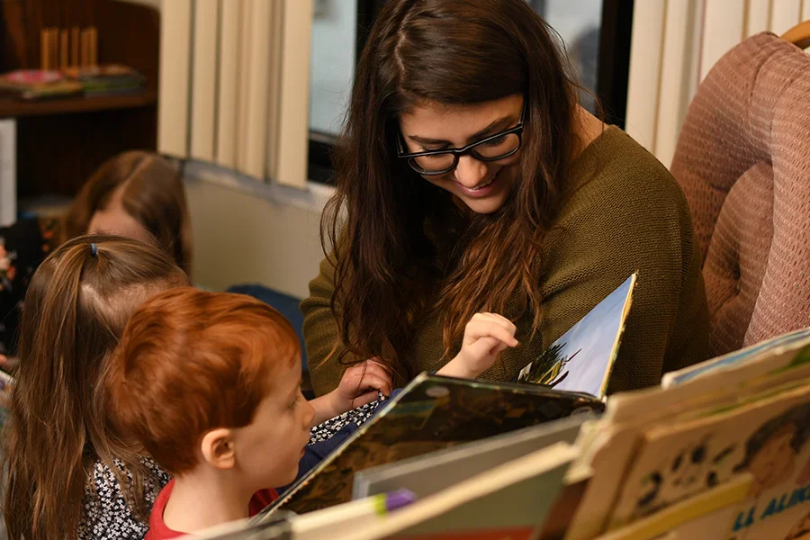 An education student reads a picture book to two young children.