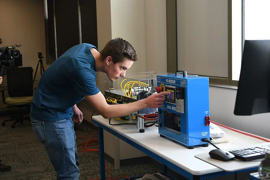 A student works on electrical equipment in a classroom.
