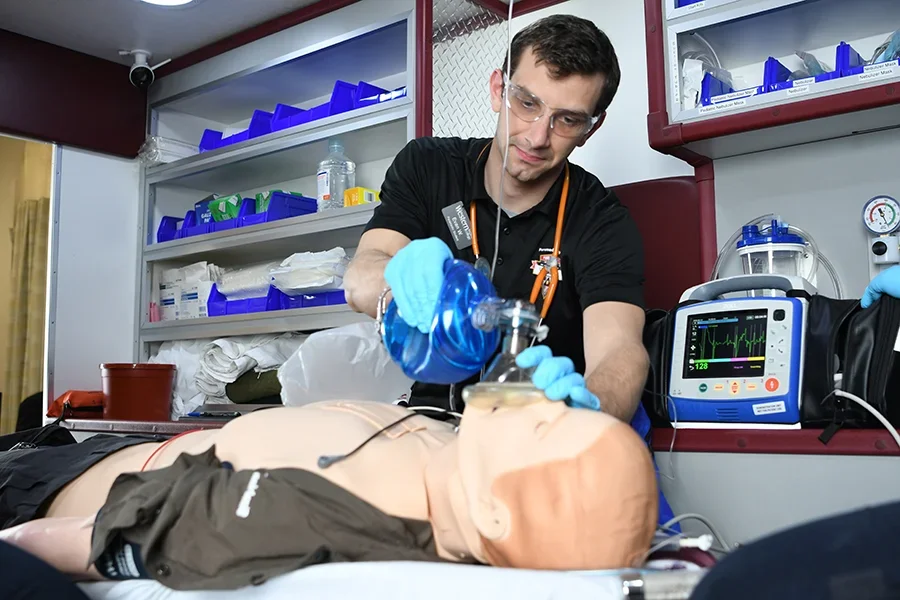 An EMT student practices techniques on a dummy in a laboratory setting.