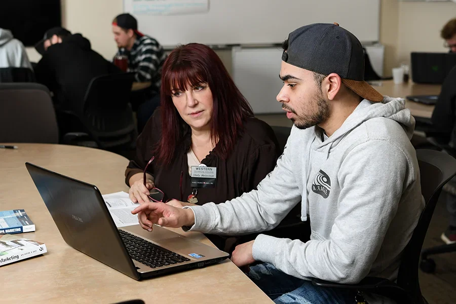 Students work together at a laptop discussing class material.