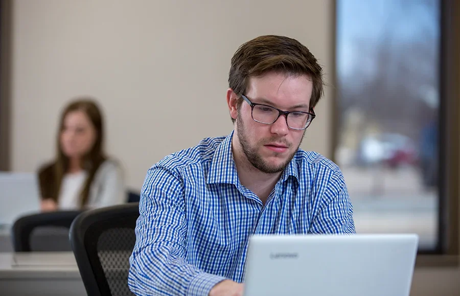 An HR student works on his computer in a classroom.