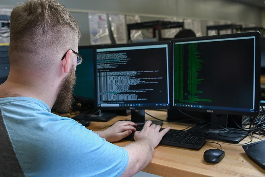 A programmer works on code across multiple computer monitors.
