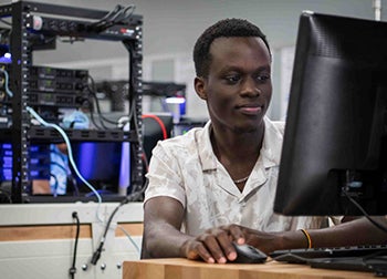 An IT student works at a computer in a lab.