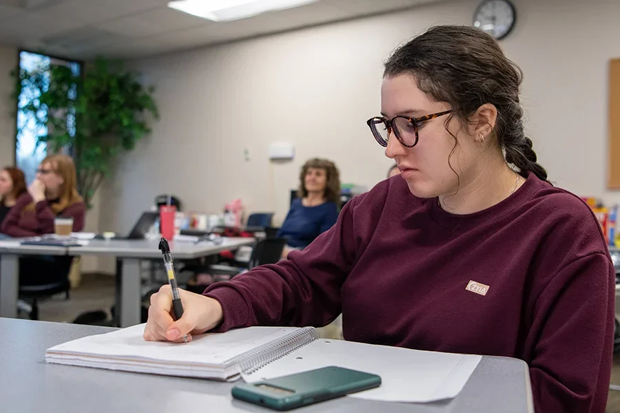 Student taking notes in classroom.