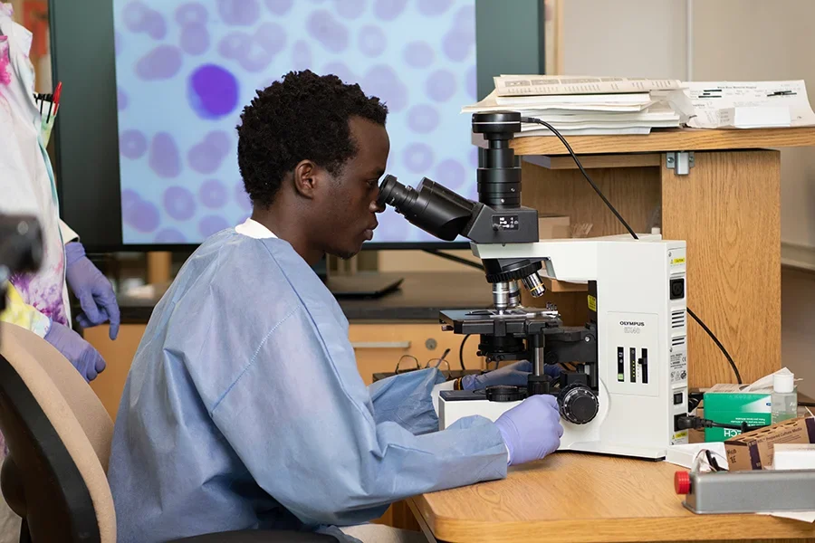 Student looking into microscope in classroom