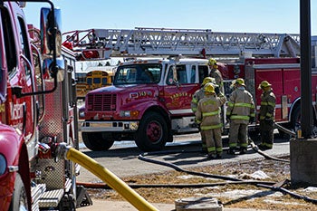 Firefighters huddled near a firetruck giving and taking instructions.