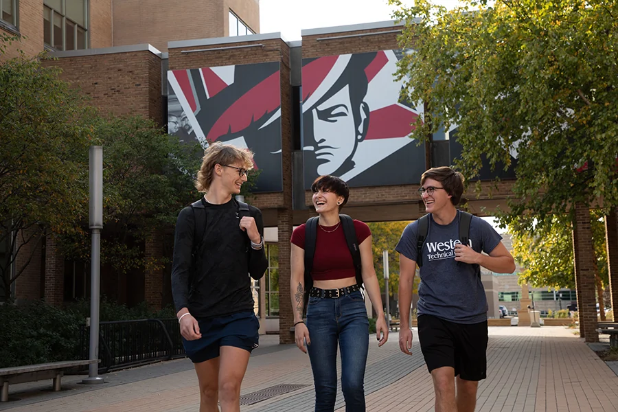 Three Western students walk and talk in the Cleary Courtyard