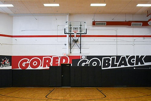 The gym has basketball courts and hoops for team games.