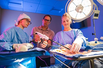 Surgical technology students work with their instructor in a surgical suite