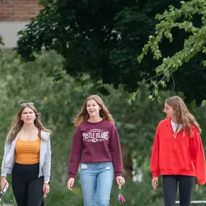 Three female students, walking in the courtyard at Western