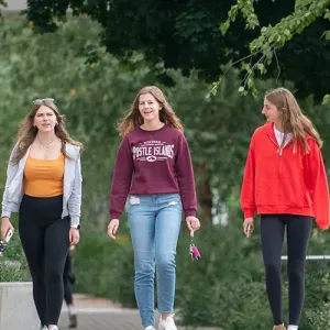 Three female students, walking in the courtyard at Western