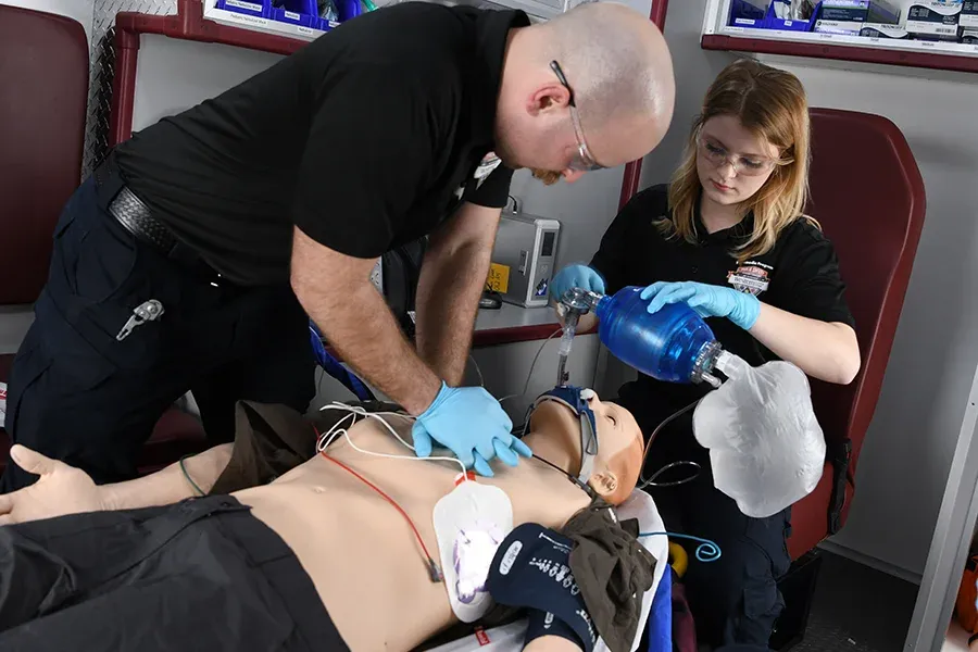 EMT students practice resuscitation techniques on a dummy.