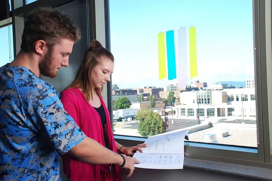 Students brainstorming together with Post-Its on a window.