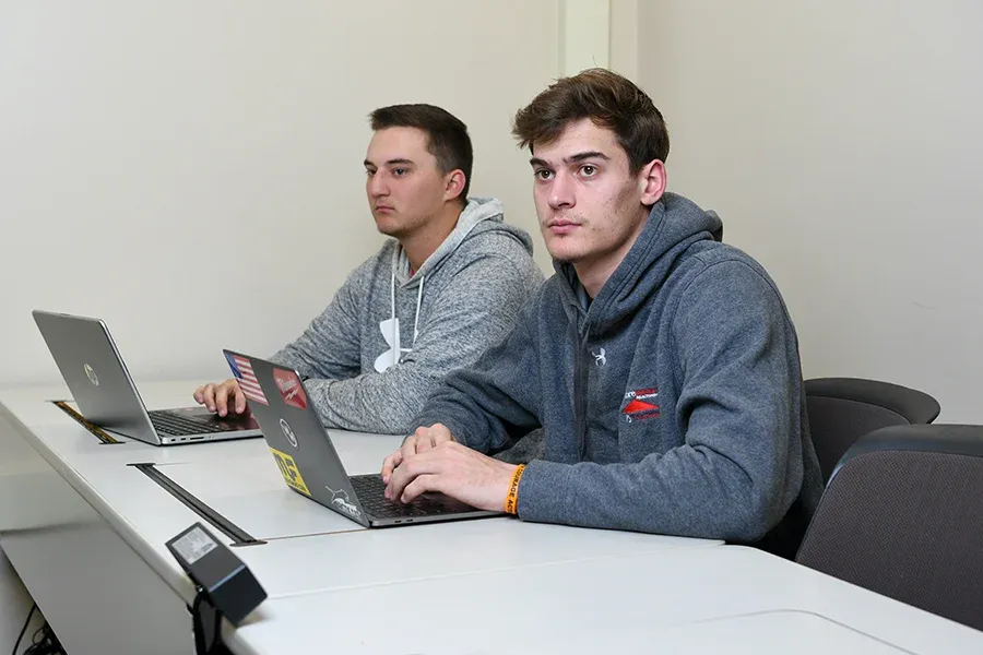 Two students listen to a lecture in a classroom.