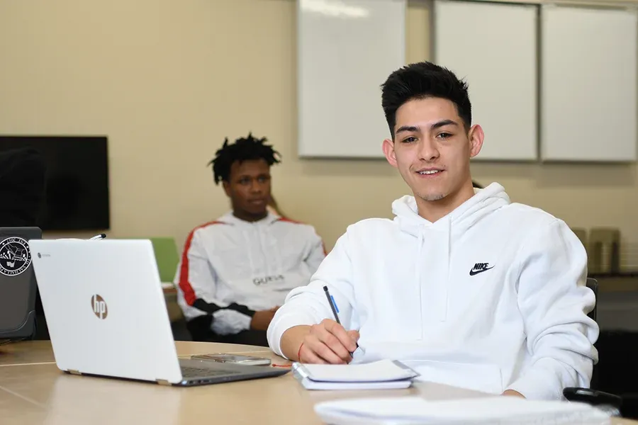 A student works at a laptop in a classroom.