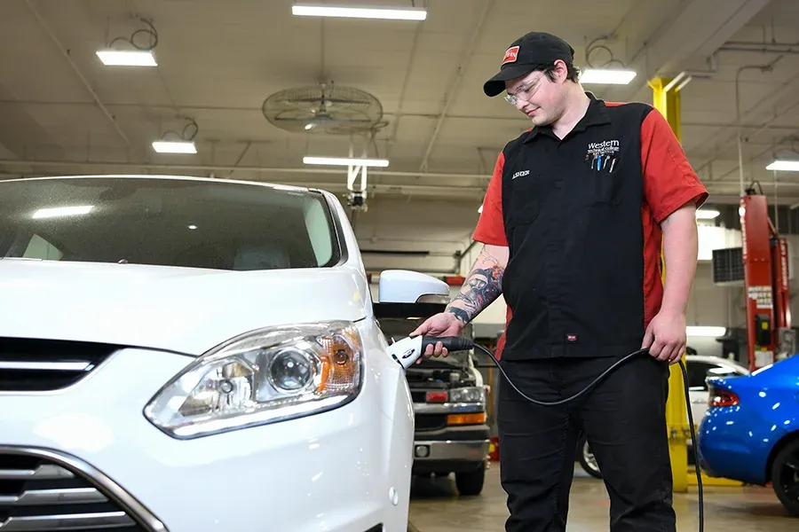 A student charges an electric car in the auto shop.