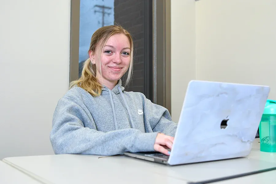 A business student works on her laptop in a classroom.