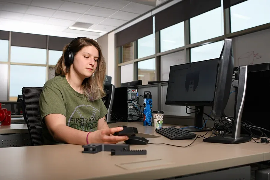 A designer works at a computer station in a classroom.