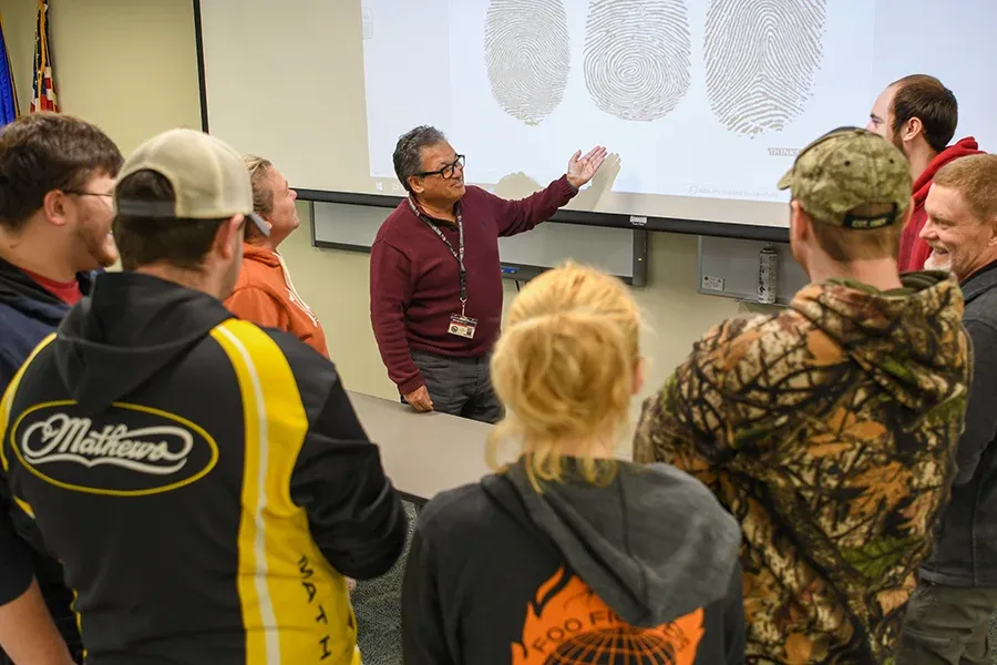 An instructor lectures to a group of students about fingerprinting.