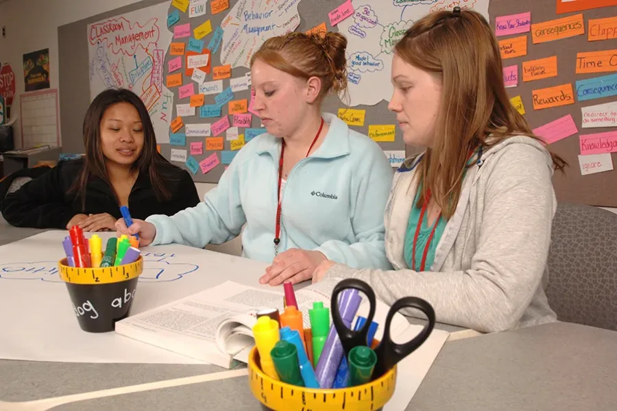 Three education students collaborate on an art project.