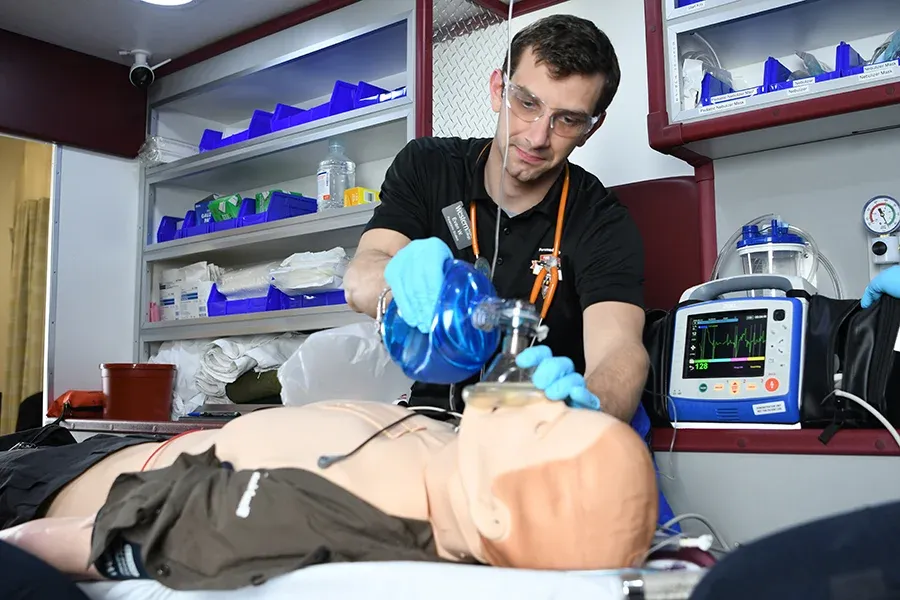 An EMT student practices techniques on a dummy in a laboratory setting.