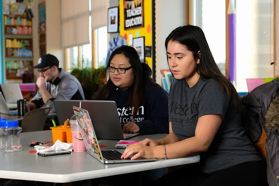 Students work on laptops in a common space.