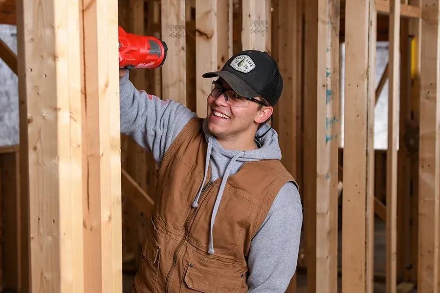 A Building Construction & Cabinetmaking student works on a frame of a building