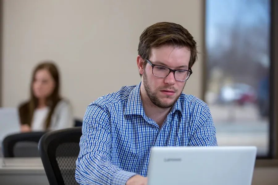An HR student works on his computer in a classroom.