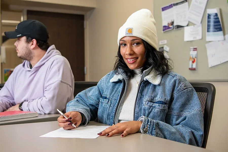 A student takes an exam in a classroom.