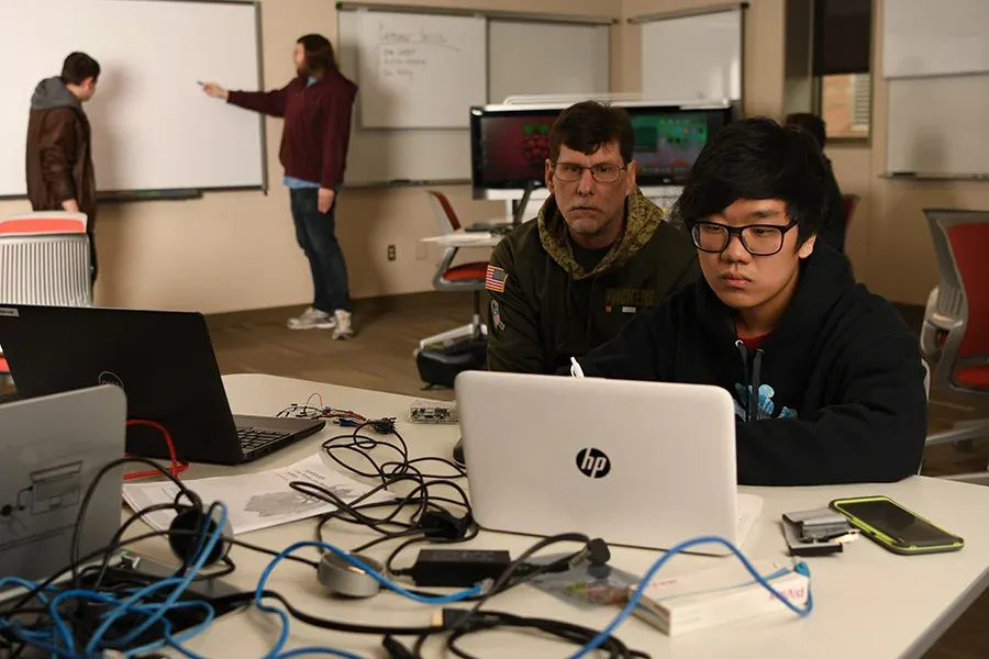 IT students work together at a computer station.