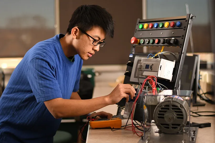 A student works with electronic mechanical equipment in a classroom.