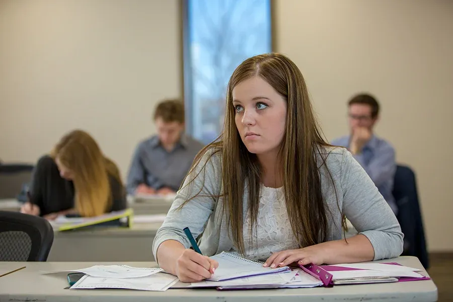 Student taking notes in a classroom.