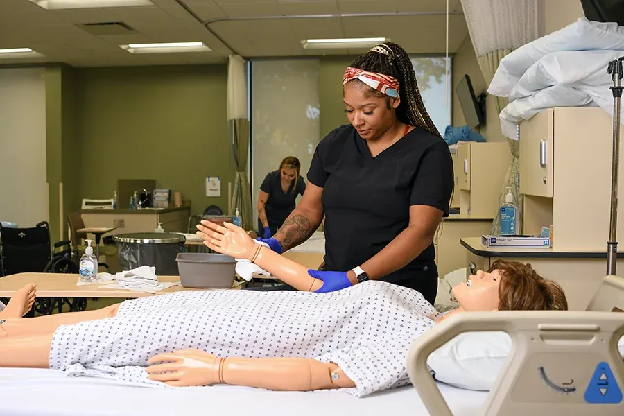 Student practicing on hospital doll in classroom