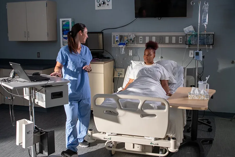 Nursing student looking at patient in hospital bed