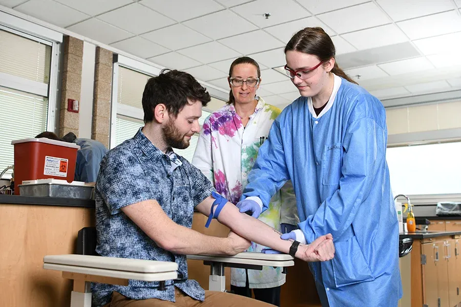 Student practicing on patient with teacher behind