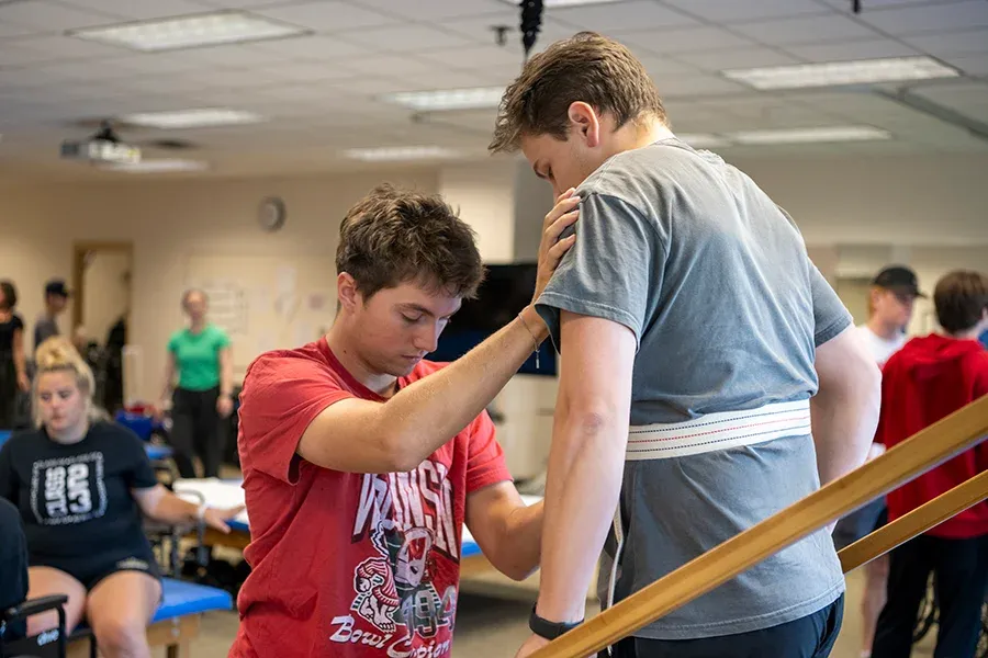 Two students practicing physical therapy exercises in class