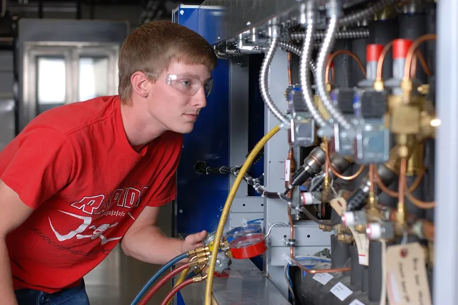 Student looking at wire system on back of machinery