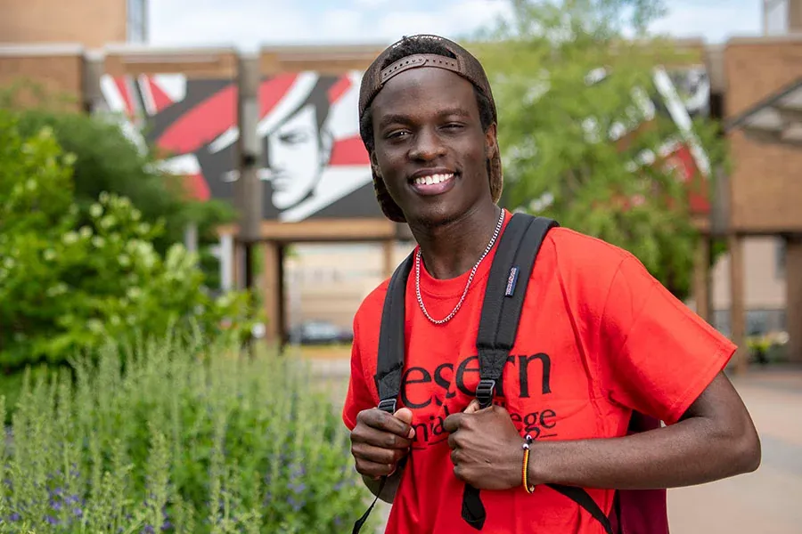 A male student stands in the Cleary Courtyard, with greenery and Western buildings in the background