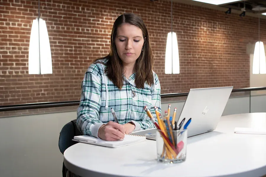 A student with a laptop studies outside at Western