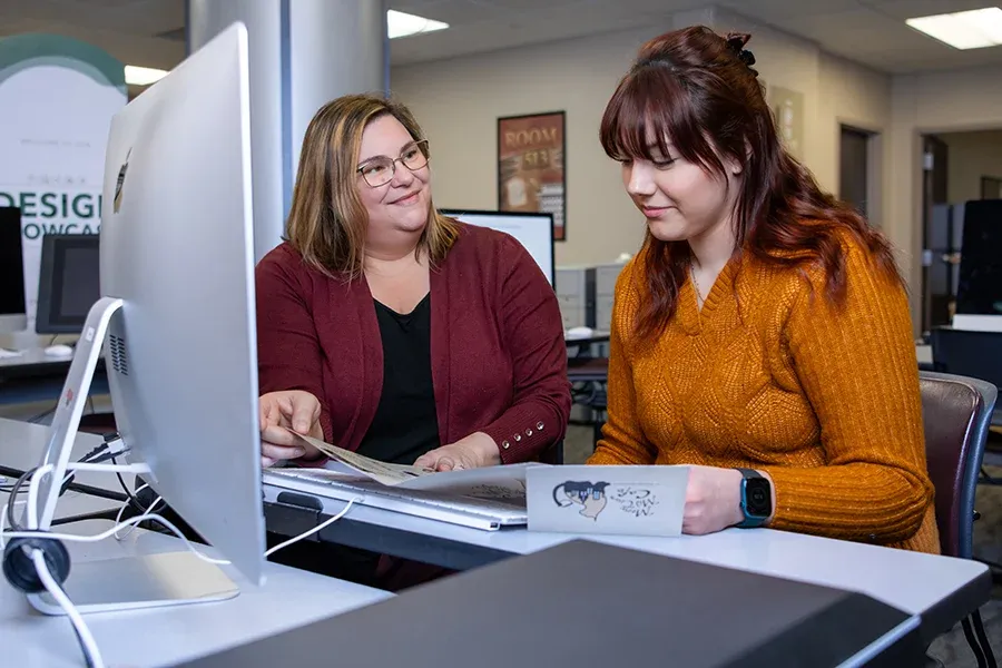Teacher showing student something by computer