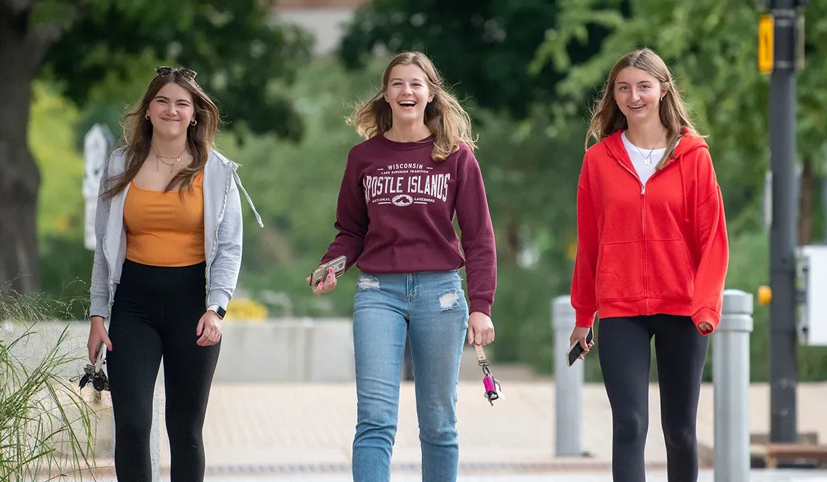 Three female students, walking in the courtyard at Western
