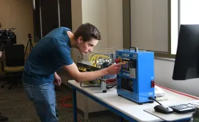 A student works on electrical equipment in a classroom.
